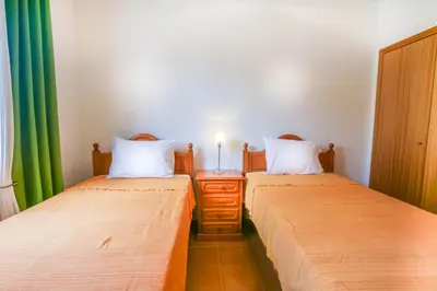 two twin beds in a room with green curtains at Hadassa Sunrise Refuge in Porto Santo