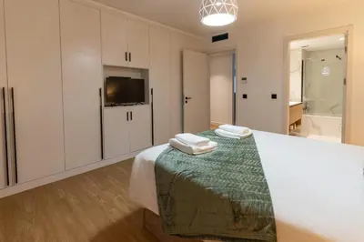 a bedroom with a bed and a tv and a bathroom at São Lucas apartamento com piscina e parking no Funchal in Funchal