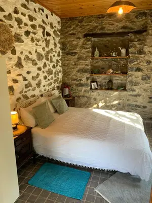 a bedroom with a bed and a stone wall at Pico Paraiso Madeira in Ponta do Sol