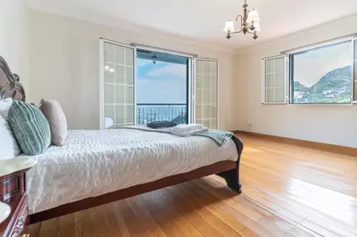 a bedroom with a bed and a large window at Varandas da Caldeira by Madeira ReAL in Câmara de Lobos