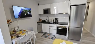 a kitchen with a table and a stainless steel refrigerator at TIME OFF Madeira in Funchal