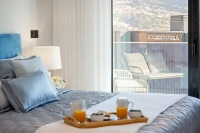 a bed with a tray with two glasses of orange juice at City View Condo in Funchal