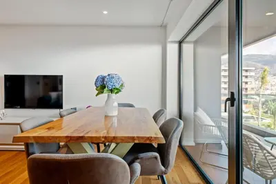 a dining room table with chairs and a vase of flowers at City View Condo in Funchal