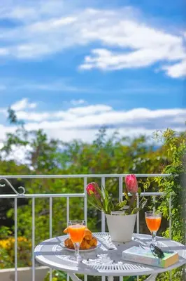 a table with two wine glasses and a vase with roses at Atelier by Real Vision in Funchal