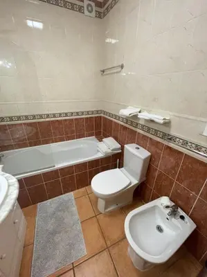 a bathroom with a toilet and a tub and a sink at Superbe appartement vue mer et falaises in Lagos