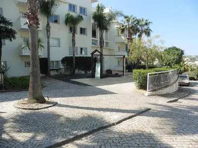 a building with a gate and a tree in front of it at Superbe appartement vue mer et falaises in Lagos