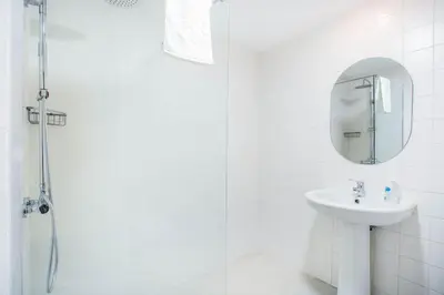 a white bathroom with a sink and a mirror at Cantinho dos Netos in Funchal