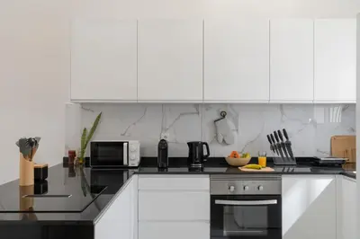 a kitchen with white cabinets and a stove top oven at Casa Areia Dourada by An Island Apart in Porto Santo