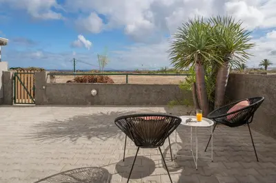 a patio with two chairs and a table and a palm tree at Casa Areia Dourada by An Island Apart in Porto Santo