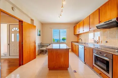 a large kitchen with wooden cabinets and a large window at Alcantara Bell in Feiteiras