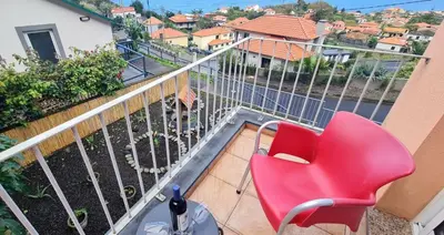 a red chair sitting on top of a balcony at Alcantara Bell in Feiteiras