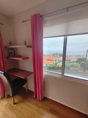a room with a window with a desk and a red curtain at Alcantara Bell in Feiteiras