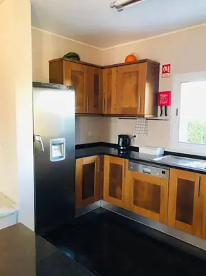 a kitchen with wooden cabinets and a black refrigerator at DAR Arrifana- Stylish 4-Bedroom Villa -Ocean Views in Aljezur