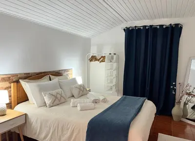 a bedroom with a large bed with blue curtains at Quiet Cozy Apt MQ2 & Near Beach & Mountain View in Calheta
