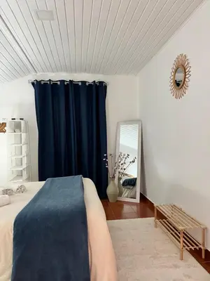 a bedroom with a blue curtain and a mirror at Quiet Cozy Apt MQ2 & Near Beach & Mountain View in Calheta