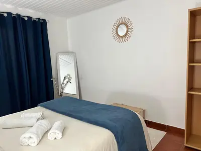 a bedroom with a bed with blue curtains and a mirror at Quiet Cozy Apt MQ2 & Near Beach & Mountain View in Calheta