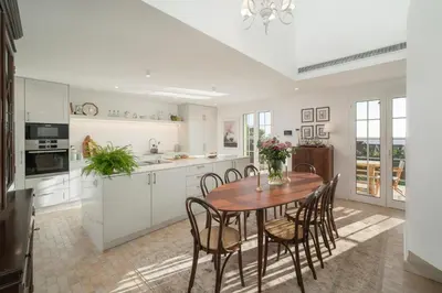 a kitchen with white cabinets and a wooden table and chairs at Quinta Marefe - On the stunning west coast in Paul do Mar