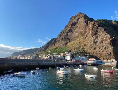 a group of boats in the water near a mountain at Quinta Marefe - On the stunning west coast in Paul do Mar