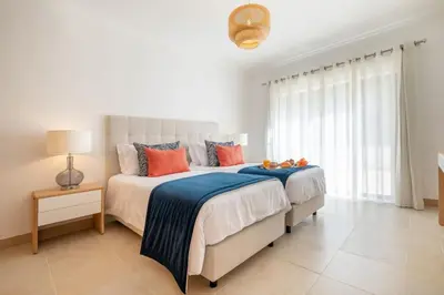 two beds in a white bedroom with orange and blue pillows at Paradise Beach Villa by Blue Diamond 18 in Lagos
