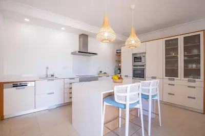 a kitchen with white cabinets and white counters and stools at Paradise Beach Villa by Blue Diamond 18 in Lagos