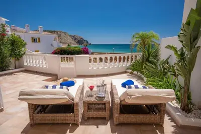 a patio with a table and chairs and the ocean at Beachfront Apartment Praia da Luz by Blue Diamond 23B in Luz