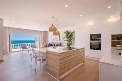 a kitchen with white cabinets and a large island with chairs at Beach View Apartment Praia da Luz by Blue Diamond 24-1F in Luz