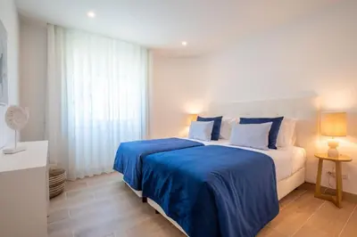 a white bedroom with a large bed with blue sheets at Beach View Apartment Praia da Luz by Blue Diamond 24-1F in Luz