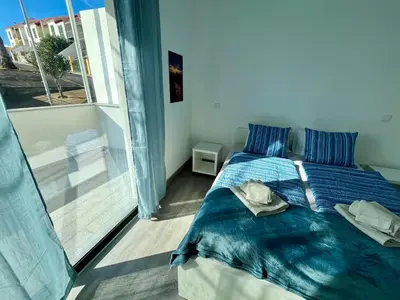 a bedroom with a bed with blue sheets and a window at SCIROCCO SUITES Madeira - Ocean View in Água de Pena