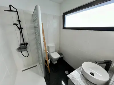 a bathroom with a toilet and a sink and a window at SCIROCCO SUITES Madeira - Ocean View in Água de Pena