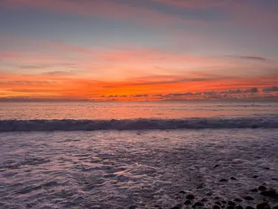 a sunset on the beach with the waves at A Casa da Minha Mãe in Paul do Mar