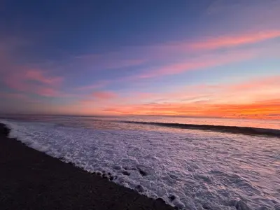 a sunset on the beach with the ocean at A Casa da Minha Mãe in Paul do Mar