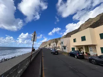 a street next to the ocean with cars parked at A Casa da Minha Mãe in Paul do Mar
