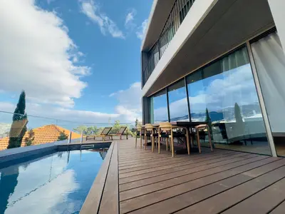 a deck with a table and chairs next to a swimming pool at Blue Boat by Madeira Best Apartments in Funchal