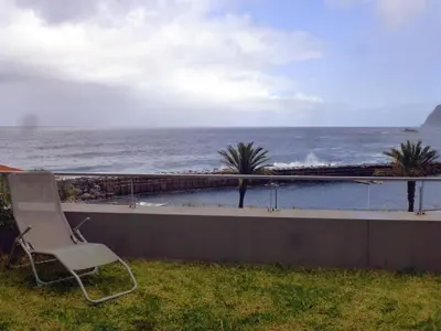 a chair sitting on a wall looking at the ocean at CASAS MARE , Ponta Delgada, Madeira in Ponta Delgada