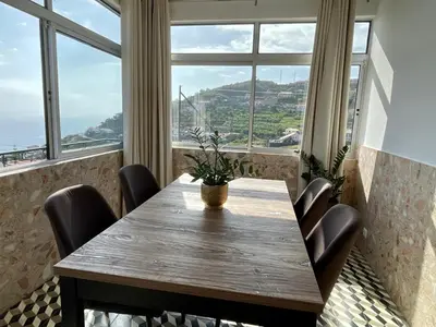 a table and chairs in a room with windows at Vila Verde in Tábua