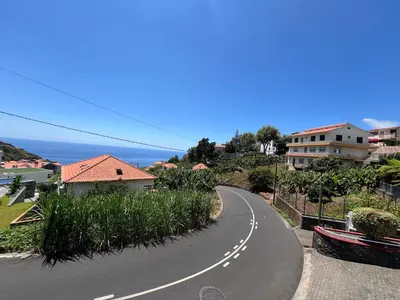 a winding road with houses and the ocean in the background at Casa Nova - Maison avec garage, terrasse & Balcon in Ponta do Sol