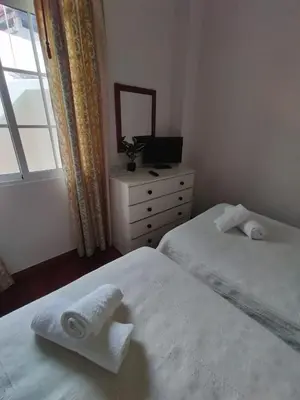 a bedroom with two beds and a dresser and a window at Hortasol A in Funchal