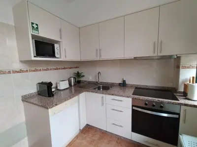 a kitchen with white cabinets and a black appliance at Hortasol A in Funchal