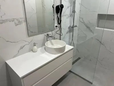 a bathroom with a glass shower door and a sink at Maribel's Place in Funchal