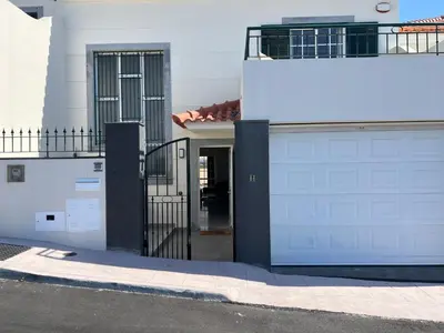 a white house with a gate and a garage at Maribel's Place in Funchal