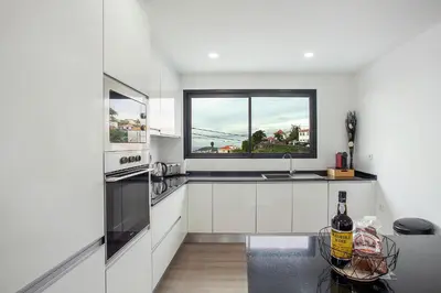 a white kitchen with a sink and a window at Villa Angela in Funchal