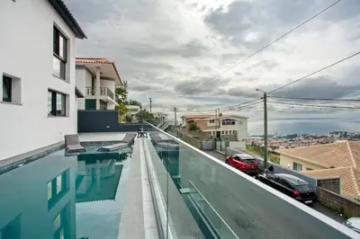 a patio with wicker chairs and a table on a balcony at Villa Angela in Funchal