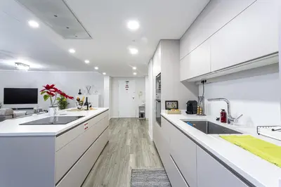 a kitchen with white counters and sinks and a tv at Imperatriz Madeira Apartment in Funchal