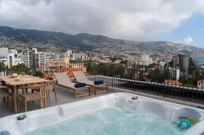 a hot tub on a balcony with a table and chairs at Green Boat by Madeira Best Apartments in Funchal