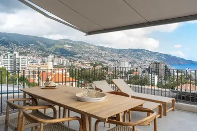 a wooden table and chairs on a balcony with a view at Green Boat by Madeira Best Apartments in Funchal