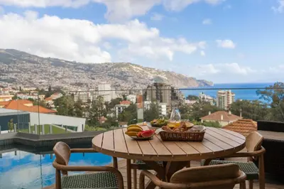 a table with a basket of fruit on a balcony at Green Boat by Madeira Best Apartments in Funchal