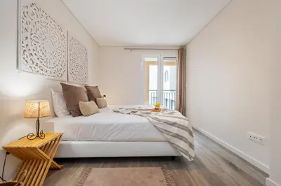 a white bedroom with a bed and a window at Carmo Heritage Apartments in Funchal