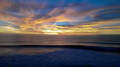 a sunset over the ocean with a wave at The Wave House - Oceanfront in Jardim do Mar