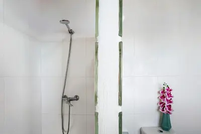 a shower in a bathroom with a vase of flowers at The Wave House - Oceanfront in Jardim do Mar