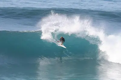 a man riding a wave on a surfboard in the ocean at Original Wave House in Jardim do Mar